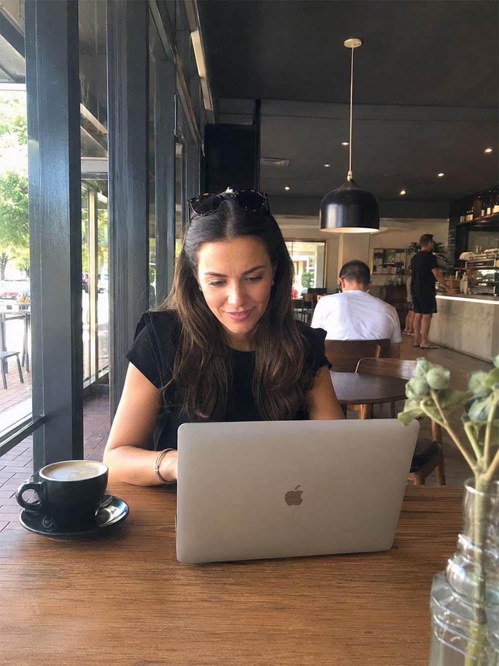 Woman using a laptop in a Melbourne café while working on SEO strategy for local business visibility.