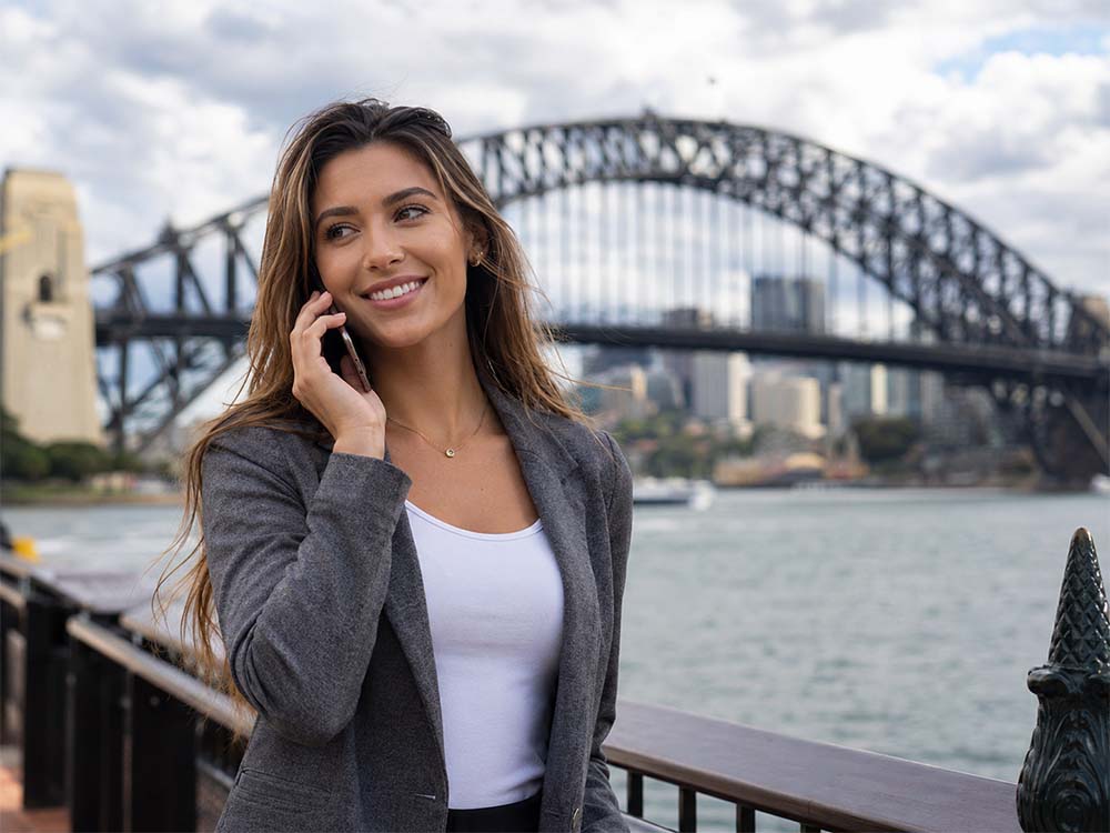 Business woman on the phone near Sydney Harbour Bridge for SEO Sydney services