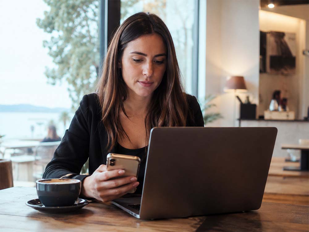 Professional woman using a laptop and phone while reviewing SEO Geelong strategy for local business rankings and enquiries.